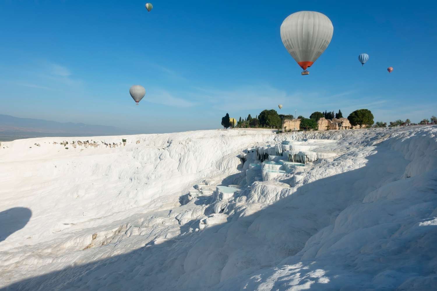 Pamukkale is one of the most exquisite displays of the beauty of nature that you can imagine. White travertine terraces of bright blue water and snow-white limestone decorate the valley sides of Pamukkale, known as the ‘Cotton Castle’. These unique natural formations make a trip to Pamukkale an unmissable highlight of any tour of Turkey. These natural pools were formed as a result of centuries of limestone erosion by thermal springs, and the mineral-rich water of Pamukkale’s pools have long-since attracted visitors thanks to their reputedly therapeutic properties. Hierapolis, the ancient city built around Pamukkale’s natural pools, pays testament to this, as it was constructed around the 2nd-century BC as a spa town to make the most of the warm, mineral-rich waters of this region.